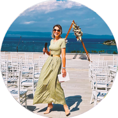 Photo of Host Tatiana with a microphone against the backdrop of a beach in Halkidiki